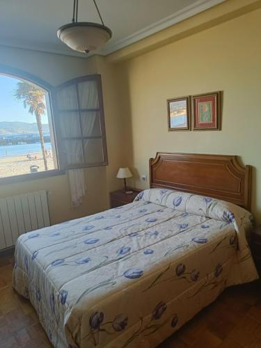a bedroom with a bed with a view of the beach at Apartamento PANXOLIÑAS in Panjón