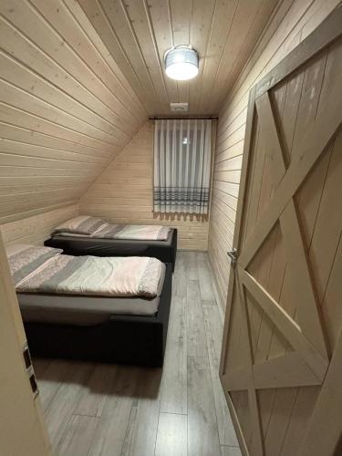 a bedroom with two beds in a wooden room with a door at Skrzynia in Skrzynia