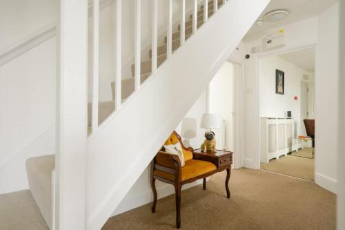 a living room with a chair under the stairs at 19th Century House Private Parking nr Painswick in Painswick