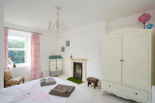 a white bedroom with a bed and a fireplace at 19th Century House Private Parking nr Painswick in Painswick