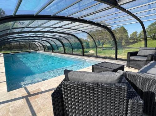 une piscine avec un toit voûté et un patio avec des chaises dans l'établissement La Millière - Piscine & Campagne - Lescure, à Le Poiré-sur-Vie