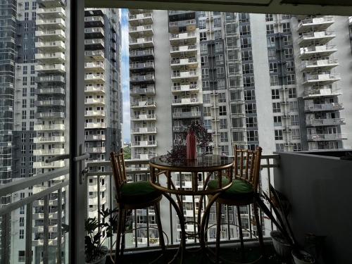 a table and chairs on a balcony with tall buildings at Kasara Serenity Condotel in Manila