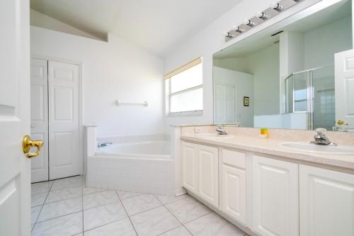 a bathroom with two sinks and a tub and a mirror at casa em orlando perto da disney com piscina house in area disney in Kissimmee