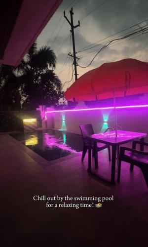 a pink lighted patio with a table and chairs at Cascade Farmhouse in Kārli