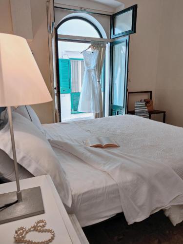 a bedroom with a bed with a dress hanging in a window at B&B Palazzo del Capitolo - By I Bastioni San Domenico in Gallipoli