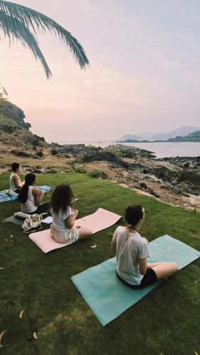 a group of people sitting on the grass practicing yoga at Secret Hill in Canacona