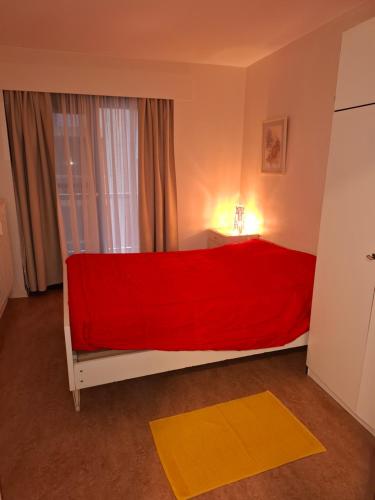 a bedroom with a red bed with a window at Appartment Jupiter 3E in Blankenberge