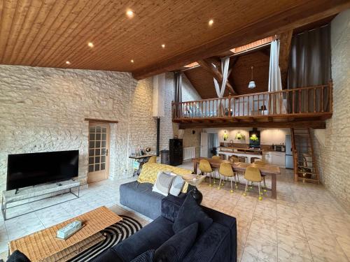 a living room with a blue couch and a tv at Gîte 100m2- piscine partagée in Meursac