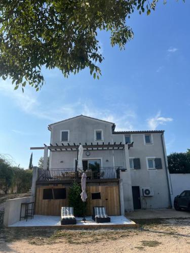 Cette maison blanche dispose d'un balcon et de 2 chaises. dans l'établissement Villa 10 P piscine lagon avec vue époustouflante proche Uzès, à Saint-Maximin