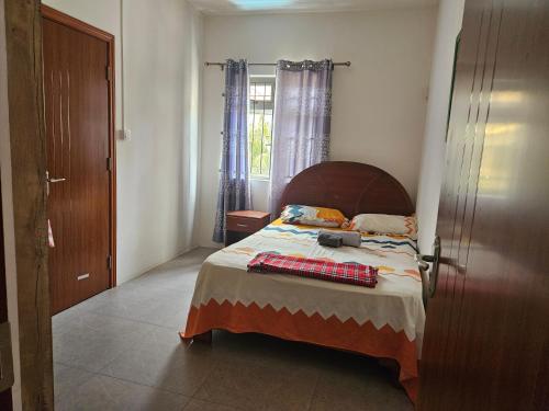 1 dormitorio con 1 cama con cabecero de madera y ventana en Residence Les Manguiers Fully equipped, en Flic en Flac