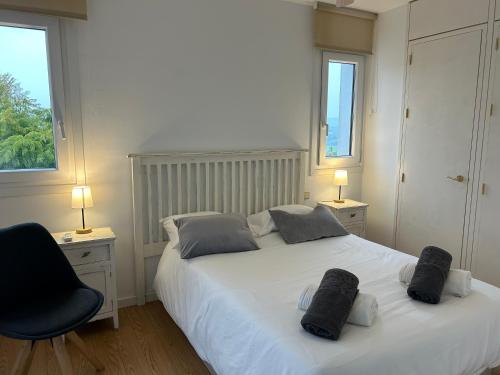 1 dormitorio con 1 cama blanca con silla negra y 2 ventanas en Sotogrande apartamento duplex, en Sotogrande