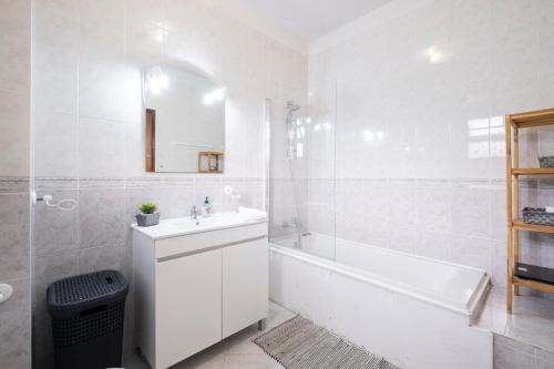 een witte badkamer met een bad, een wastafel en een bad bij De Casa Villa by GALMI in Estreito da Calheta