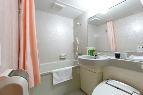 a bathroom with a sink and a toilet and a mirror at Spring Sunny Hotel Nagoya Tokoname ekimae in Tokoname