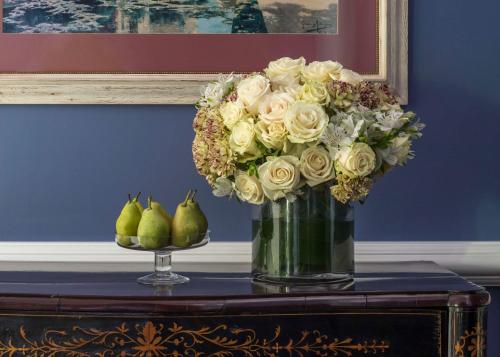a vase filled with white roses and pears on a table at Anantara Villa Padierna Palace Benahavís Marbella Resort - A Leading Hotel of the World in Estepona