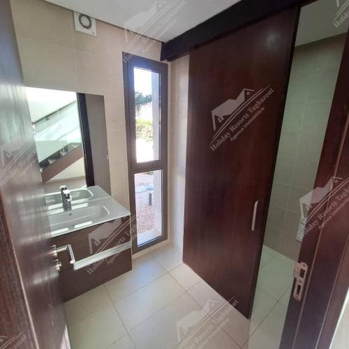bagno con porta, lavandino e specchio di Thé Blue Pearl Villa Ocean View Taghazout Bay Amda a Taghazout