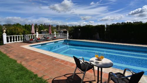 a swimming pool with chairs and a table next to it at Villa Delta by Casitas Select in Córdoba