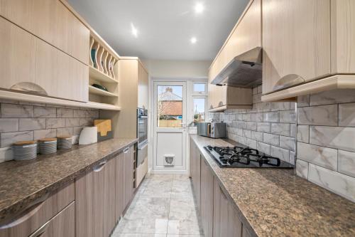 a kitchen with wooden cabinets and a stove top oven at Cooper House Stay - Large Stylish House in Oxford
