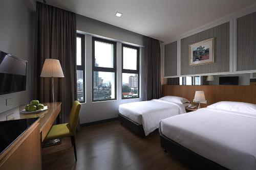 a hotel room with two beds and a desk at Hotel Transit Kuala Lumpur in Kuala Lumpur