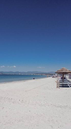 a beach with an umbrella and chairs and the ocean at Pindemonte 52 appartament in Quartu SantʼElena