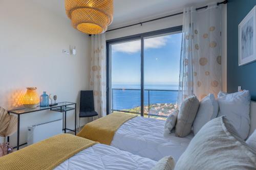 ein Schlafzimmer mit einem Bett und einem großen Fenster in der Unterkunft Ocean and Palms in Arco da Calheta