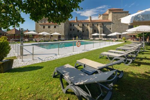 a row of lounge chairs next to a swimming pool at Hotel & Spa Monasterio de Boltaña in Boltaña