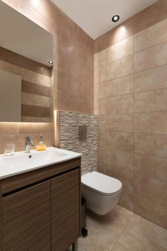 a bathroom with a sink and a toilet and a mirror at Rhodes Skyline Suite with out Door Jacuzzi Sea View in Ixia