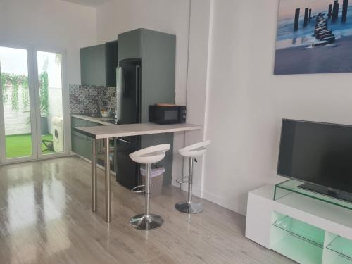 a kitchen with a bar with stools and a television at Apartment Azul in Santa Pola