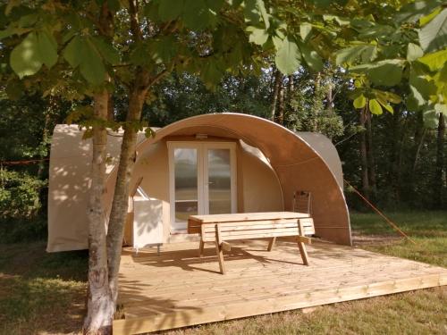 a tent with a picnic table in front of a tree at AIRE NATURELLE CAMPING LA LOIRE FLEURIE in Le Perrier