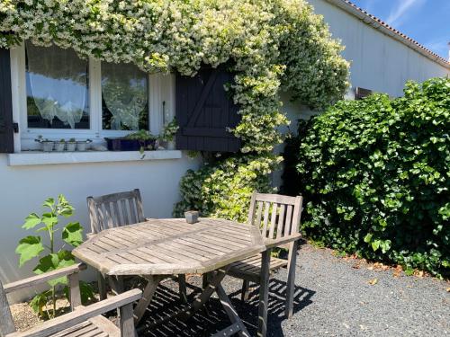 une table en bois et deux chaises en face d'une maison dans l'établissement Villa et dépendance piscine privée, à La Jarrie