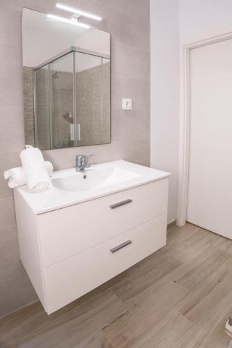 a white bathroom with a sink and a mirror at Casa Petra in Vejer de la Frontera