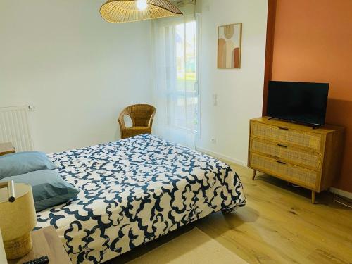 une chambre avec un lit et une télévision sur une commode dans l'établissement Appartement du Fort à Concarneau, à Concarneau