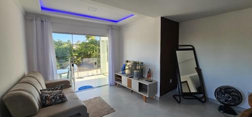 a living room with a couch and a large window at Apartamento Novo in Porto Seguro