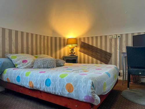 a bedroom with a bed with a colorful comforter at Au Ptit Mousse - Hôtel et Restaurant in Courseulles-sur-Mer