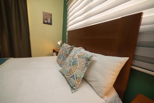 a bedroom with a bed with a wooden headboard and pillows at Hotel La Casona MC in La Romana