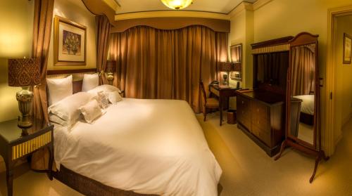 a bedroom with a large white bed and a desk at Peermont D'oreale Grande at Emperors Palace in Kempton Park