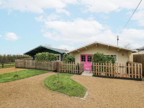 a house with a pink door and a fence at The Log Cabin in Swindon