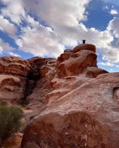 a person standing on top of a rock formation at Wadi Rum Wild Camp Desert in Wadi Rum