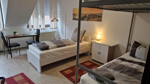 a bedroom with two beds and a table and a desk at Zimmer D in Mönchengladbach
