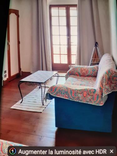 une chambre avec un canapé, une table et une fenêtre dans l'établissement Lourdes grand appartement de caractère, à Lourdes