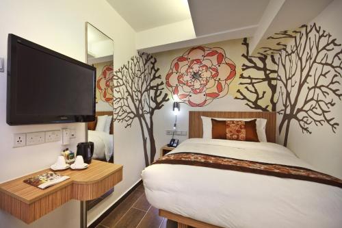 una camera da letto con letto, TV e alberi a parete di Hotel Clover The Arts a Singapore