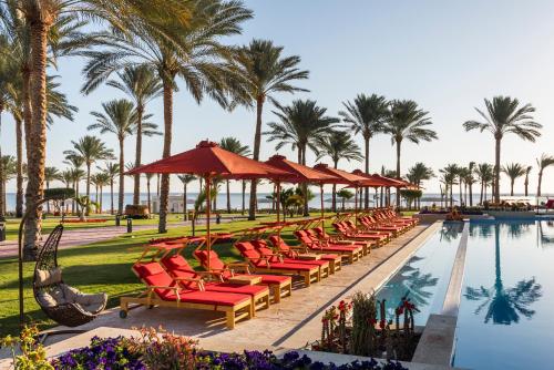 a row of chairs and umbrellas next to a pool at Rixos Premium Seagate - Ultra All Inclusive in Sharm El Sheikh