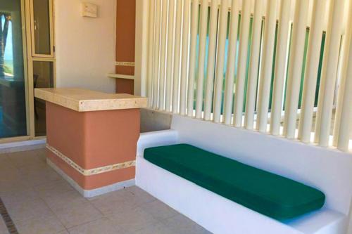 a bench with a green seat in a room at Kastelorizo Private Beachfront house in Chicxulub