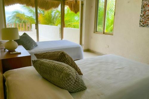 a bedroom with two beds and a lamp and windows at Kastelorizo Private Beachfront house in Chicxulub