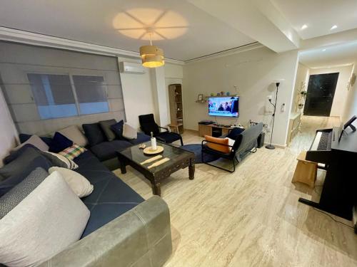 a living room with a couch and chairs and a television at Les Nuits de Miel - Marrakech in Marrakech