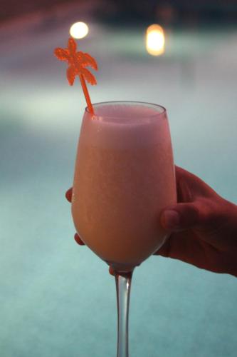 a person holding a drink with a flower on it at Las Hamacas in Canoas De Punta Sal