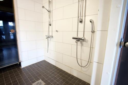 a shower in a bathroom with white tiles at Aurinko Saaga 3 in Ukkohalla
