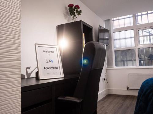 a room with a desk with a sign and a chair at SAV Apartments Rutland Leicester in Leicester