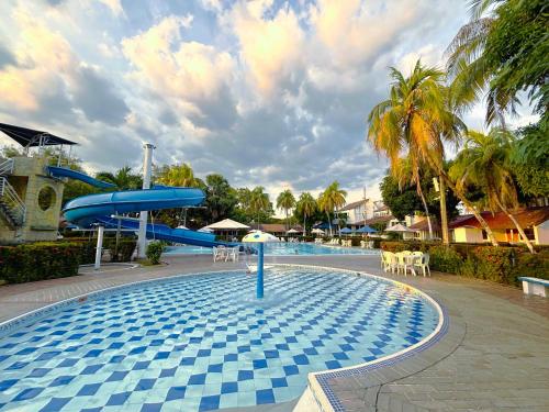 a pool with a water slide and tables and chairs at Hotel Los Puentes Comfacundi in Girardot