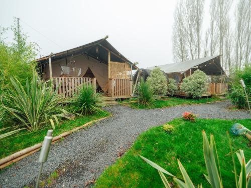 a garden with a house with a gravel driveway at Sunset Retreats Safari Tent in Ombersley