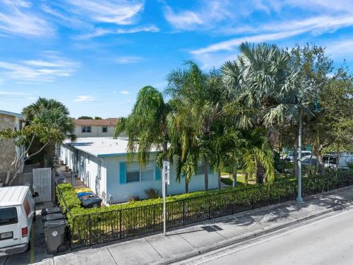 a white house with palm trees and a fence at Lake Worth Getaway- Cozy Studio - Pool in Lantana
